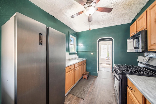 kitchen featuring appliances with stainless steel finishes, light wood finished floors, light countertops, a textured ceiling, and a ceiling fan