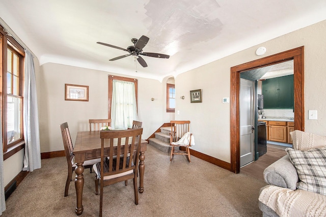 dining area featuring arched walkways, baseboards, carpet, and a ceiling fan