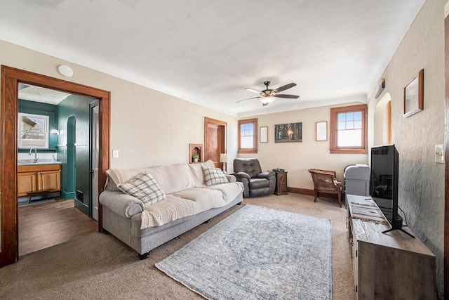 living area featuring carpet flooring and a ceiling fan