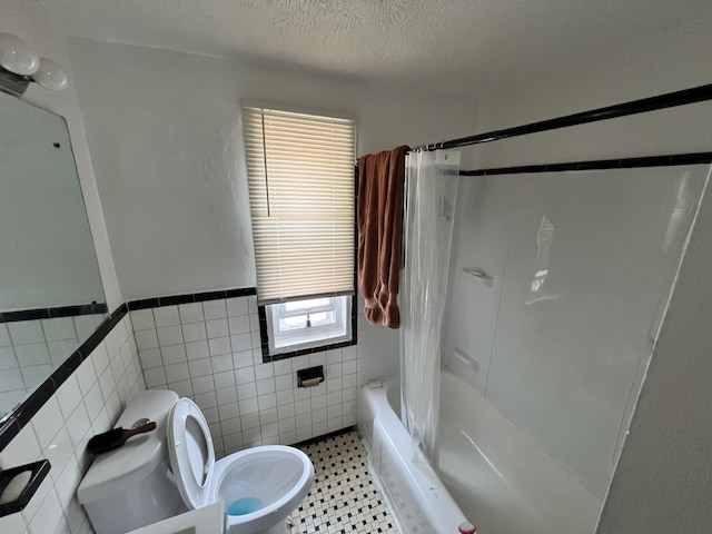 full bath featuring a textured ceiling, a wainscoted wall, shower / bath combo with shower curtain, toilet, and tile walls