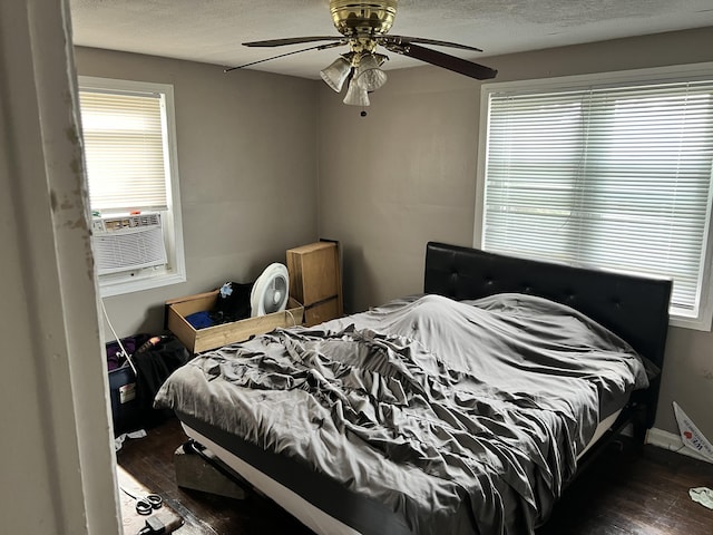 bedroom with hardwood / wood-style flooring, cooling unit, a textured ceiling, and multiple windows