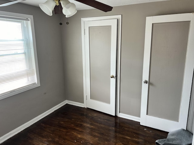 unfurnished bedroom with dark wood-style floors, ceiling fan, and baseboards