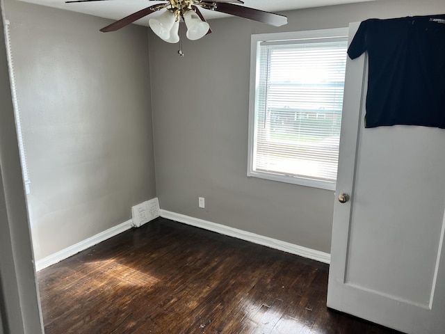 spare room featuring ceiling fan, baseboards, and dark wood-type flooring