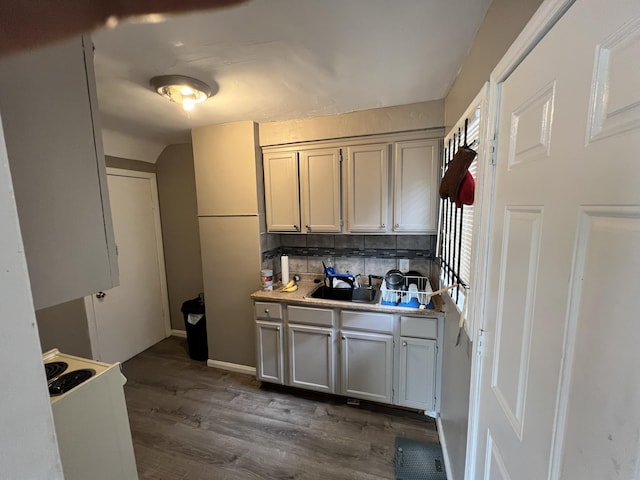 kitchen with baseboards, decorative backsplash, light countertops, a sink, and dark wood-style floors