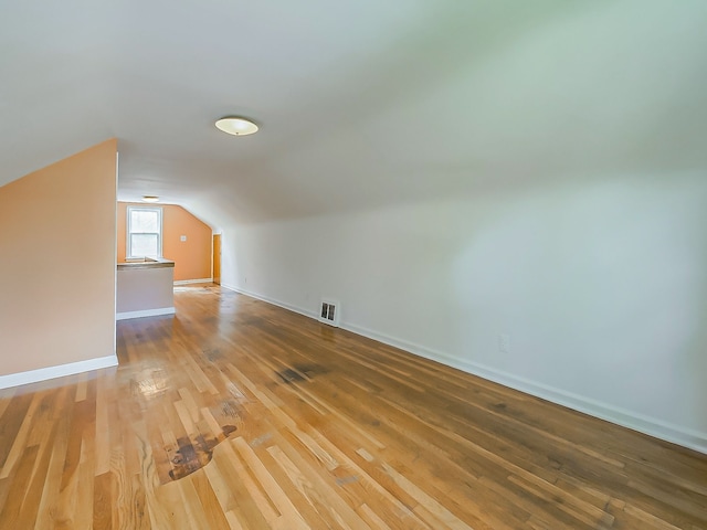 bonus room with wood finished floors, vaulted ceiling, and baseboards