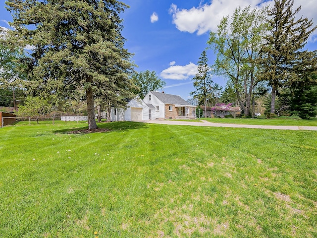 view of grassy yard with a garage and concrete driveway