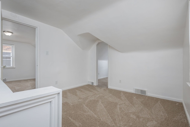bonus room with light colored carpet, visible vents, vaulted ceiling, and baseboards