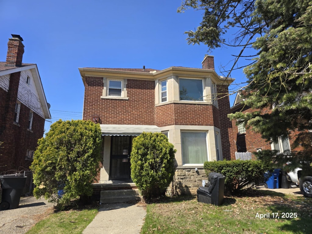 view of front of property with a chimney and brick siding