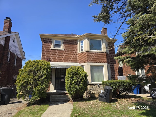 view of front of property with a chimney and brick siding