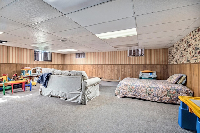 carpeted bedroom featuring wooden walls, a drop ceiling, and a wainscoted wall