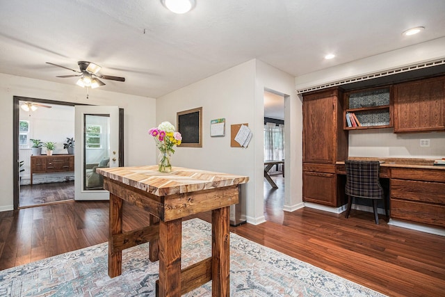 interior space featuring dark wood-style flooring, ceiling fan, baseboards, and built in study area