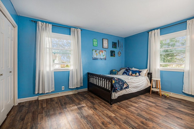 bedroom featuring hardwood / wood-style flooring, a baseboard heating unit, and baseboards