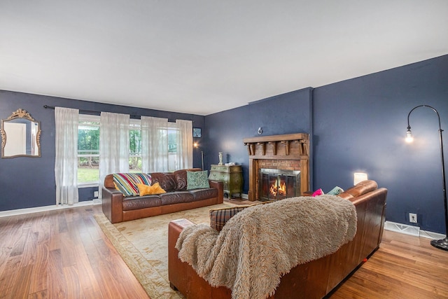 living area with a brick fireplace, wood finished floors, and baseboards