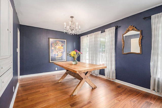 dining area featuring wood finished floors, a chandelier, and baseboards