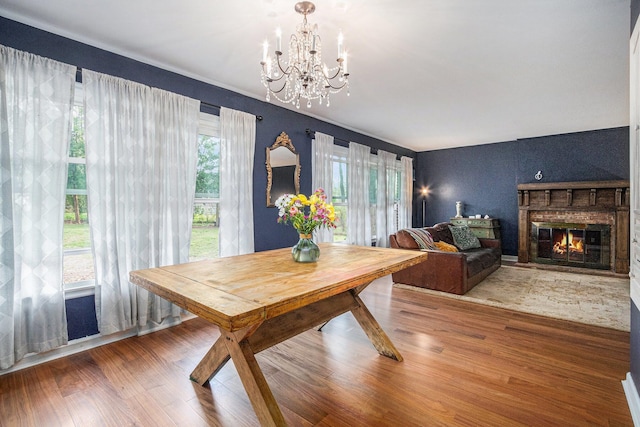 dining space with a glass covered fireplace, wood finished floors, and a notable chandelier