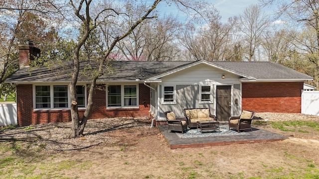 rear view of property with a chimney, brick siding, and outdoor lounge area