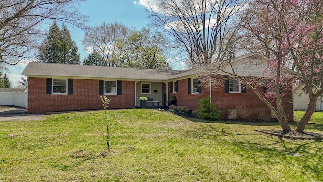 single story home with fence, a front lawn, and brick siding