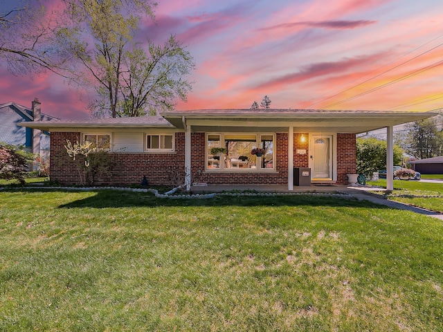 view of front of property with brick siding, a lawn, and covered porch