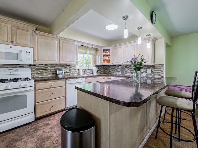kitchen with a peninsula, backsplash, white appliances, and a kitchen bar