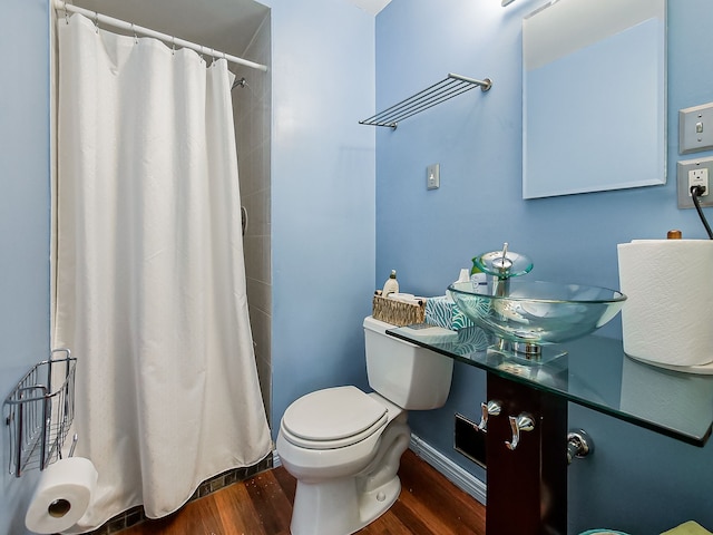 bathroom with a sink, wood finished floors, toilet, and curtained shower