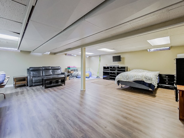finished below grade area featuring baseboards, a drop ceiling, and wood finished floors