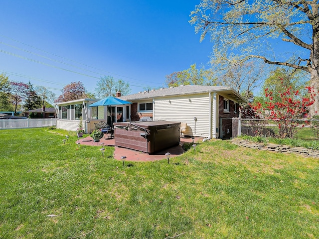 rear view of house featuring a lawn, a sunroom, a patio area, a hot tub, and a fenced backyard
