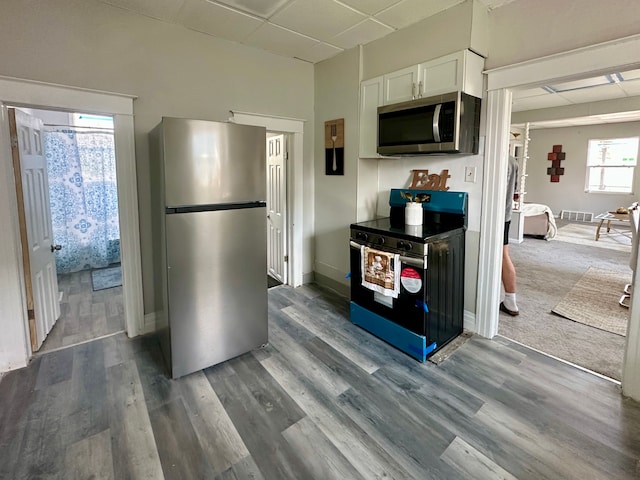 kitchen featuring white cabinetry, stainless steel appliances, wood finished floors, and a drop ceiling