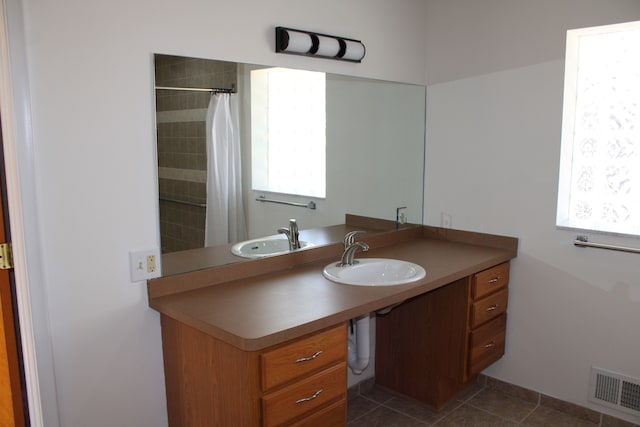 33185 Swallow Dr, Rockwood, MI 48173 - bathroom featuring a tile shower, a sink, tile patterned floors, and visible vents