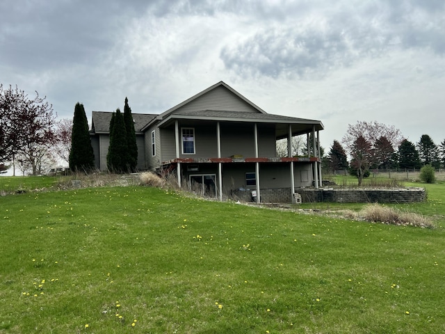 back of house featuring roof with shingles and a lawn