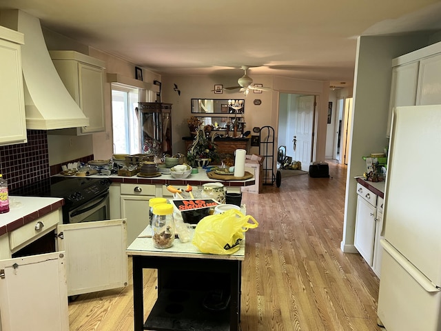 kitchen with freestanding refrigerator, electric range, ceiling fan, light wood finished floors, and tile countertops
