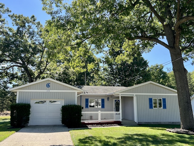 single story home with covered porch, a front yard, concrete driveway, and an attached garage