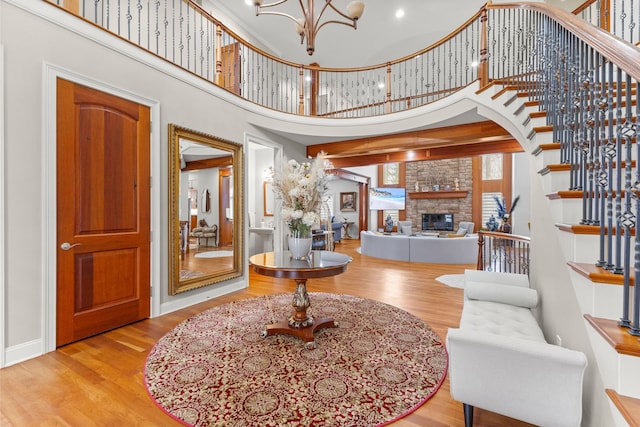 entryway featuring a towering ceiling, stairs, wood finished floors, and a fireplace