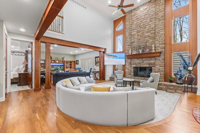 living room with a fireplace, a towering ceiling, plenty of natural light, and a ceiling fan