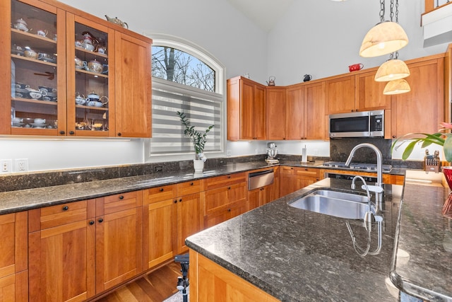 kitchen featuring dark stone counters, pendant lighting, glass insert cabinets, and stainless steel microwave