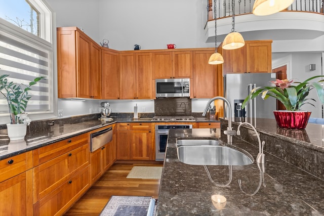 kitchen featuring a sink, a warming drawer, hanging light fixtures, appliances with stainless steel finishes, and wood finished floors