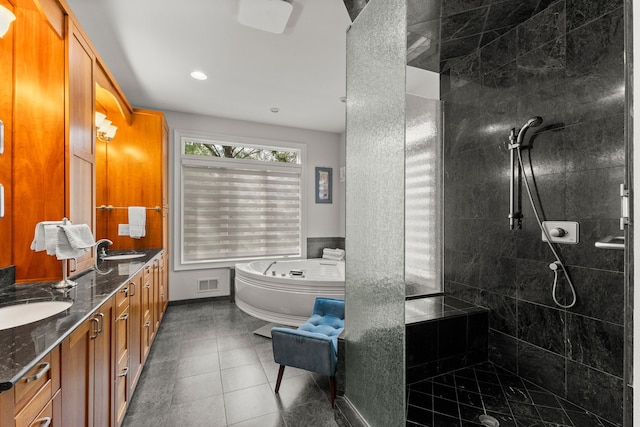 full bath with visible vents, tiled shower, double vanity, and a sink
