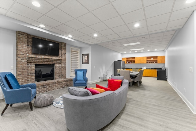 living room featuring baseboards, recessed lighting, light wood-style flooring, and a fireplace