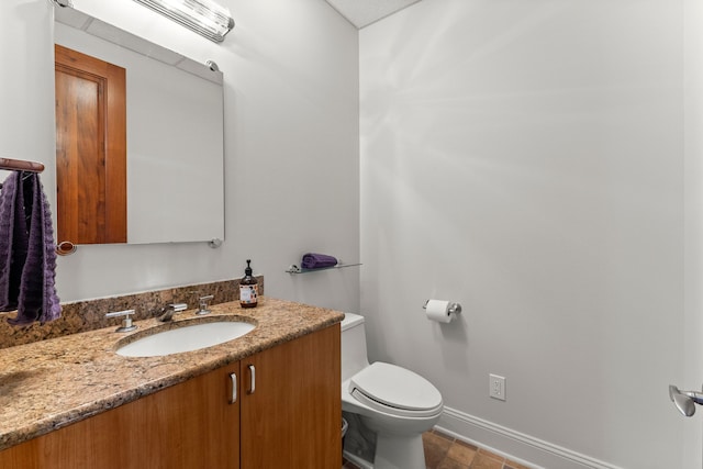 half bathroom with vanity, toilet, and baseboards