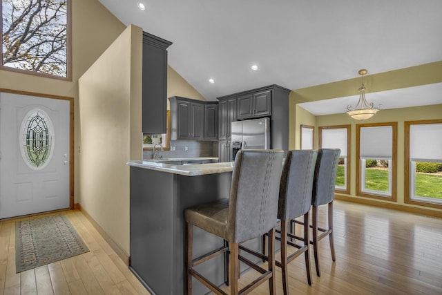 9015 Kingsley Dr, Onsted, MI 49265 - kitchen with lofted ceiling, tasteful backsplash, light wood-style flooring, gray cabinetry, and stainless steel fridge with ice dispenser