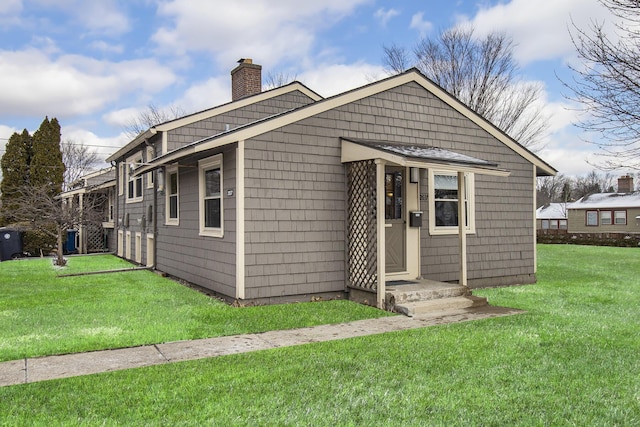 bungalow-style house featuring a chimney and a front lawn