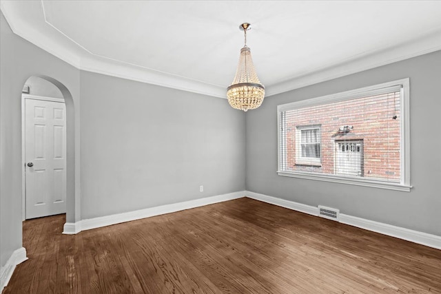 18603 Monica St, Detroit, MI 48221 - empty room featuring arched walkways, an inviting chandelier, wood finished floors, baseboards, and visible vents
