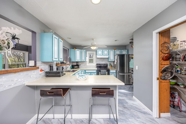 7364 Regency Ln, Canadian Lakes, MI 49346 - kitchen featuring freestanding refrigerator, a peninsula, blue cabinetry, and black electric range oven