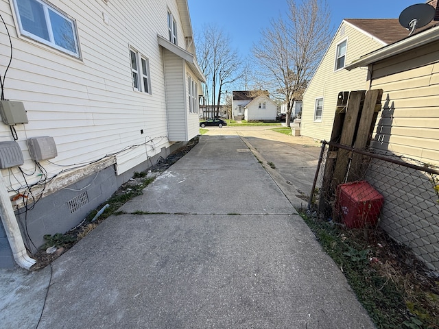view of property exterior with a residential view, concrete driveway, crawl space, and fence