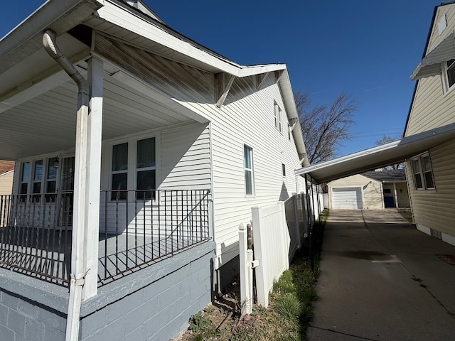 view of property exterior featuring an outdoor structure, driveway, and fence
