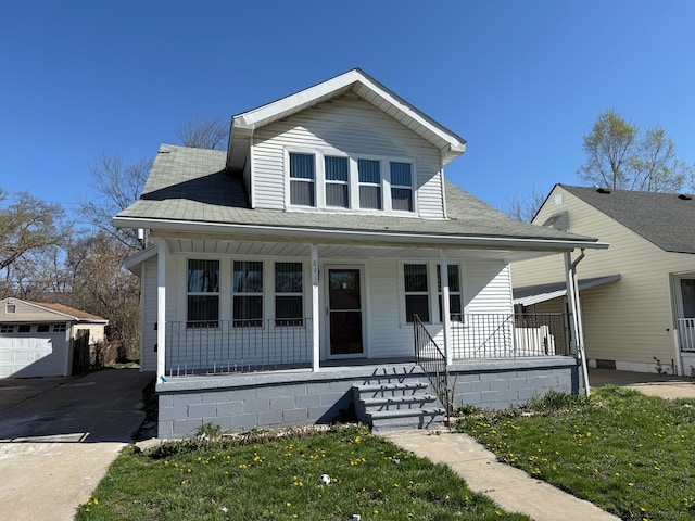 bungalow-style house featuring roof with shingles, concrete driveway, a porch, and an outbuilding