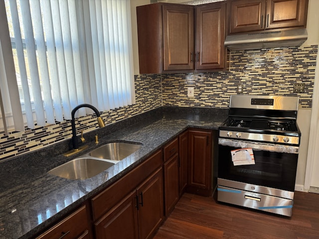 kitchen with a sink, under cabinet range hood, backsplash, and gas stove