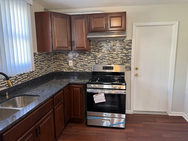 kitchen featuring a sink, stainless steel range with gas stovetop, dark wood-style flooring, under cabinet range hood, and decorative backsplash