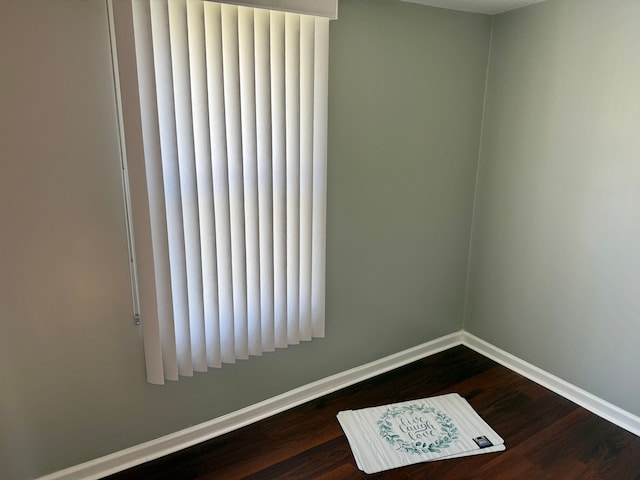 spare room with baseboards, dark wood finished floors, and radiator