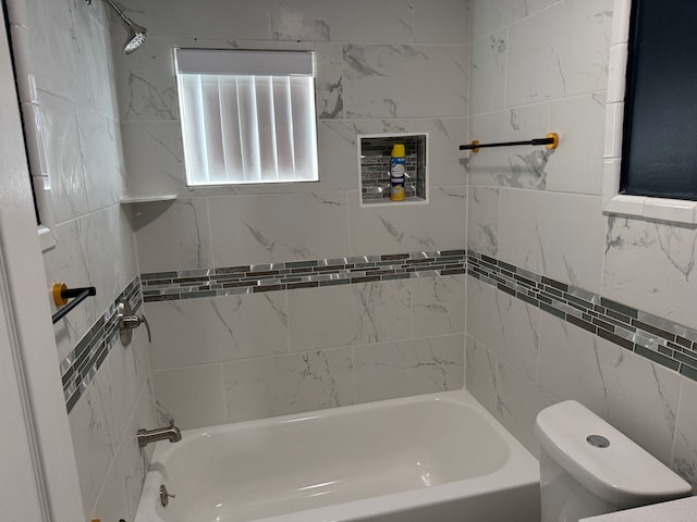 bathroom with washtub / shower combination, toilet, and tile walls