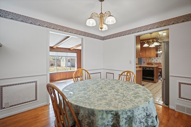 dining space with an inviting chandelier, beamed ceiling, light wood-style floors, and visible vents